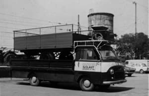 Foto d'epoca in bianco e nero: autocarro con la scritta G. CLAUT che trasporta sul cassone un rimorchio agricolo da consegnare
