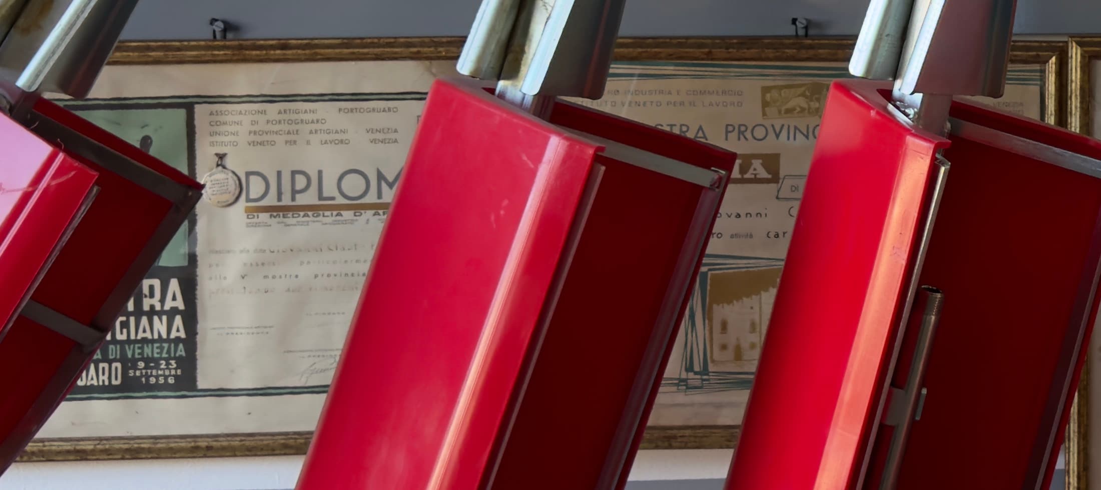 Diploma della V Mostra provinciale artigiana di Portogruaro, 9-23 settembre 1956, in cornice appeso alla parete, in parte coperto dalle campane rosse per il diserbo